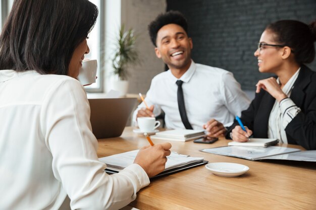 Lachende jonge collega's die binnen coworking. Focus op dame het schrijven van notities.