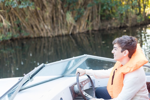Lachende jonge man achter het stuur van een boot