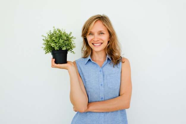 Lachende jonge mooie vrouw holding pot plant