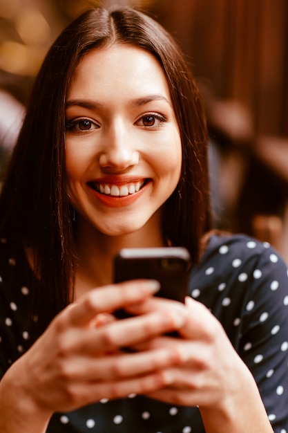 Lachende jonge vrouw met behulp van haar smartphone