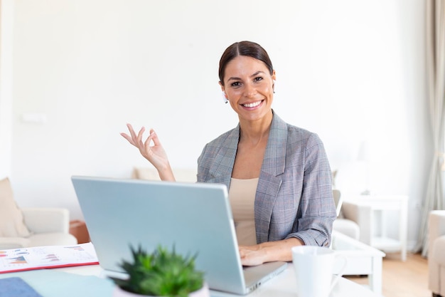 Lachende jonge vrouw met behulp van laptop thuis kijken naar scherm chatten met draadloze headset met videoconferentie business trainer tutoring door webcam online opleiding ecoaching concept