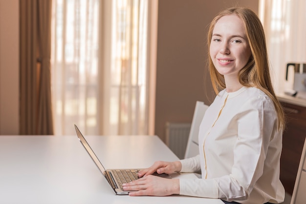 Gratis foto lachende jonge vrouw met laptop