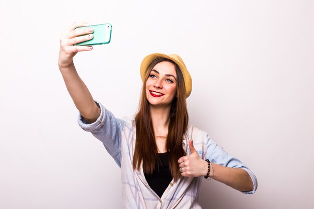 Lachende jonge vrouw selfie foto maken op smartphone over grijs