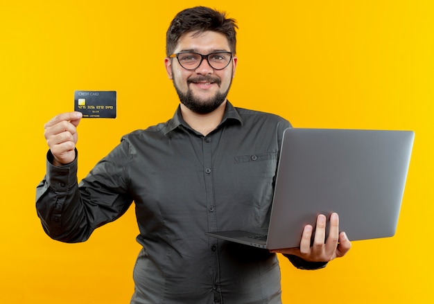 Lachende jonge zakenman bril met laptop en creditcard