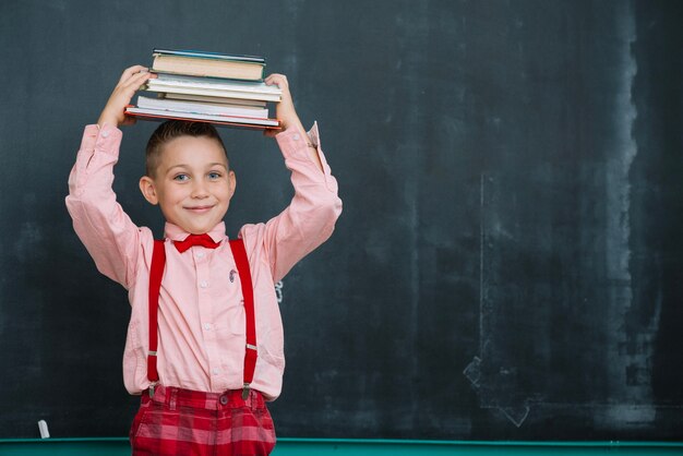 Lachende jongen met boeken op schoolbord