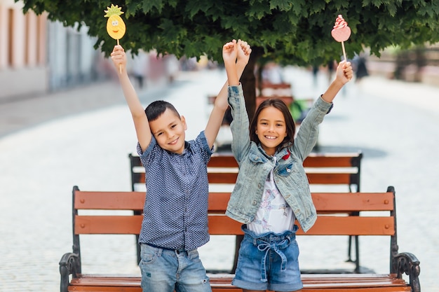 Lachende kinderen met lolly's, in de buurt van de houten bank in het park