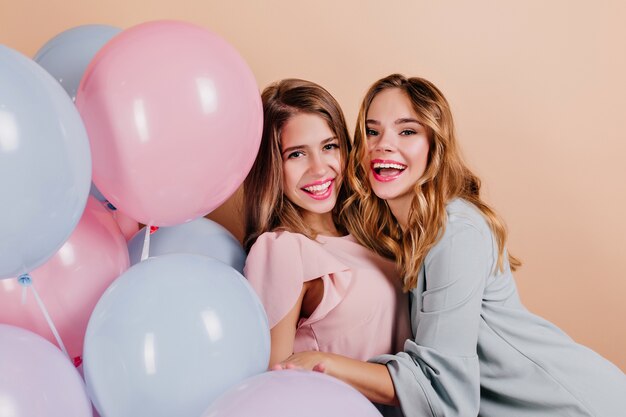 Lachende krullende dames die haar vriend omhelzen op feestje