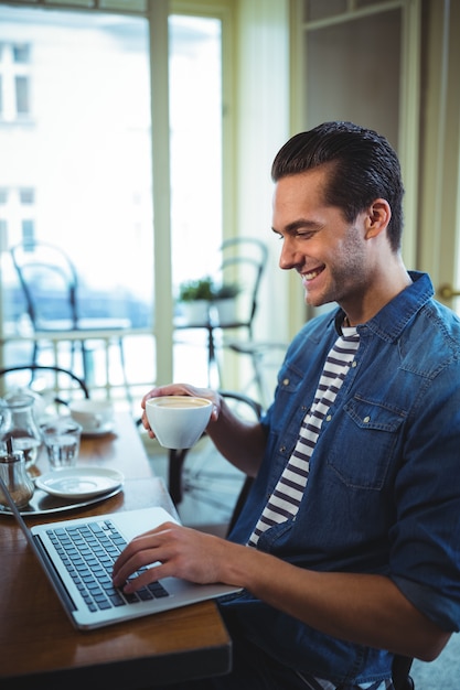 Lachende man met behulp van laptop in cafã ©