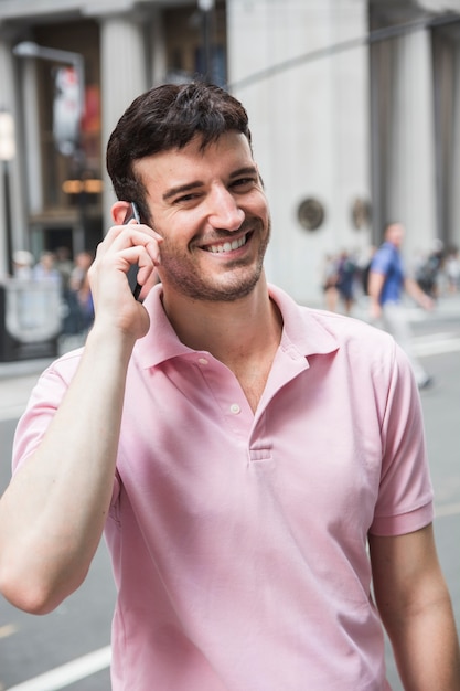 Lachende man seaking op telefoon en camera te kijken