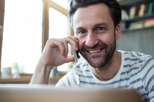 Lachende man te praten op de mobiele telefoon in de koffiebar