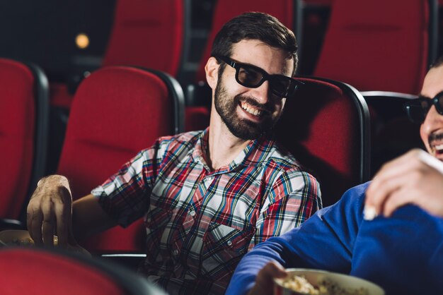 Lachende mannen die popcorn eten in de bioscoop