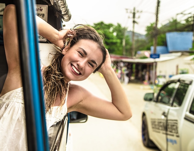 lachende meisje kijkt uit het raam van een taxi, tuk-Tuk