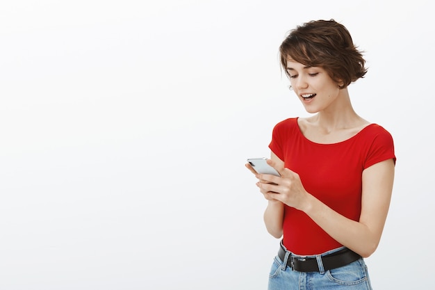 Lachende mooie vrouw met behulp van mobiele telefoon-app, bericht lezen met blij gezicht