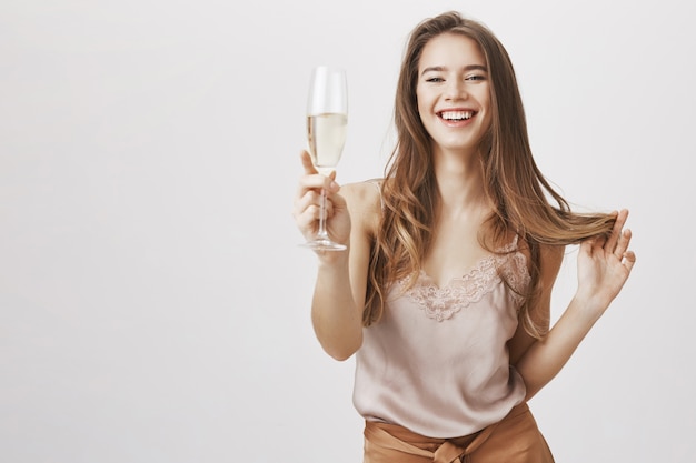 Lachende sensuele vrouw feesten met een glas champagne