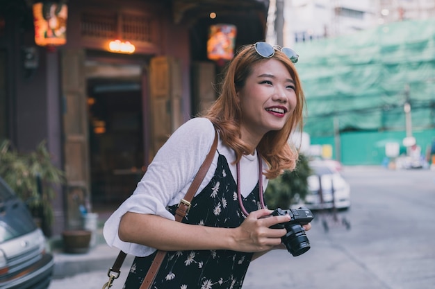 Lachende vrouw met camera die nieuwe stad onderzoekt