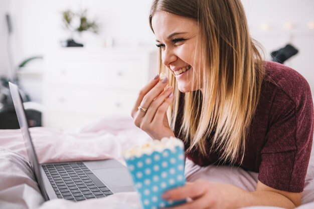 Lachende vrouw met popcorn het letten op film