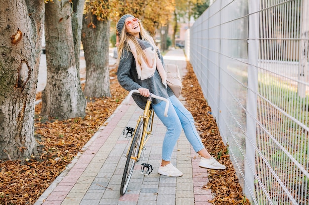 Lachende vrouw op fiets dichtbij omheining