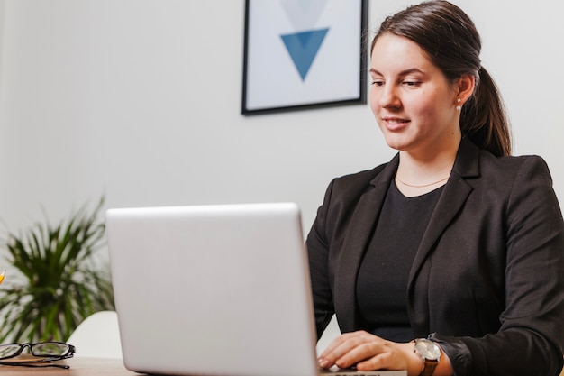 Gratis foto lachende vrouw op laptop in kantoor