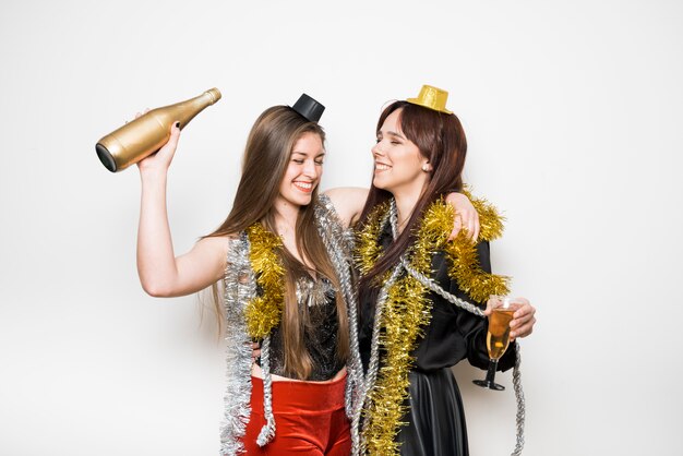 Lachende vrouwen in avondkleding met een glas drank en een fles