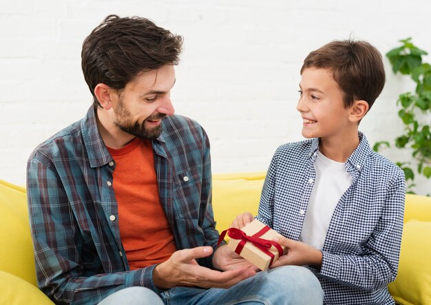 Lachende zoon biedt een geschenk aan zijn vader