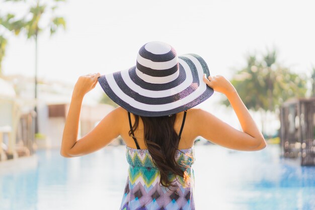 Lacht de gelukkige jonge glimlach van de portret mooie jonge Aziatische vrouw en rond zwembad in hoteltoevlucht