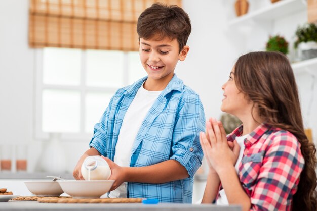 Lage hoek broer gietende melk voor zijn zus