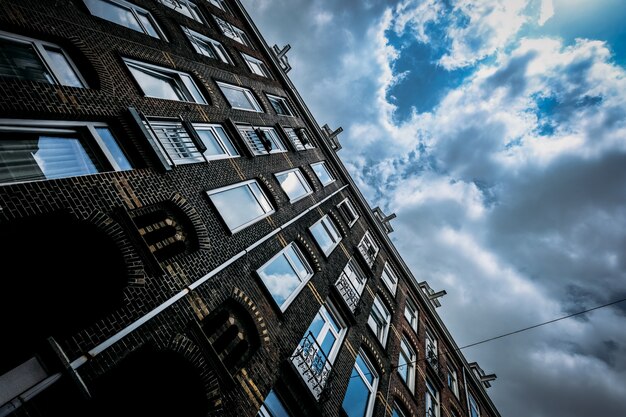 Lage hoek die van een baksteengebouw is ontsproten met vensters en een bewolkte hemel