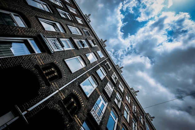 Lage hoek die van een baksteengebouw is ontsproten met vensters en een bewolkte hemel