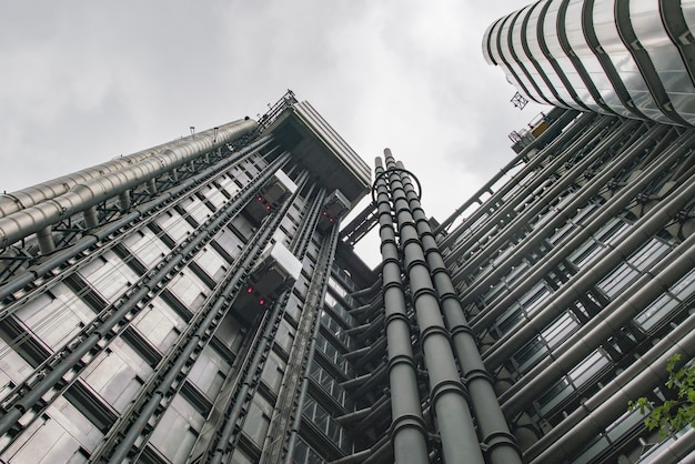 Lage hoek die van een modern grijs gebouw met glasvensters onder de duidelijke hemel is ontsproten