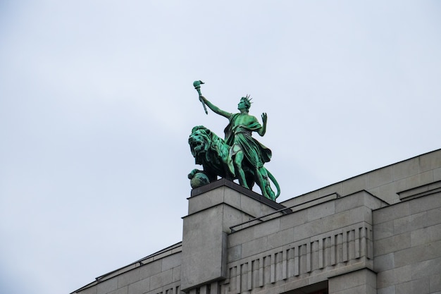 Gratis foto lage hoek die van het leeuwstandbeeld op de nationale bank van tsjechische republiek onder een bewolkte hemel is ontsproten