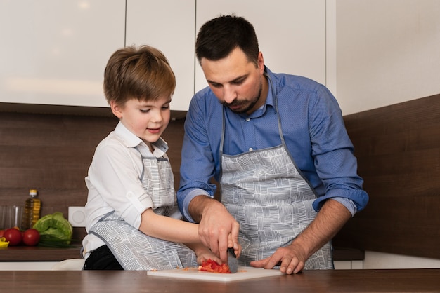 Gratis foto lage hoek kleine jongen in keuken met vader