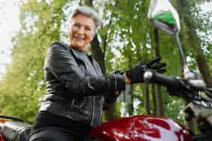 Gratis foto lage hoek oude vrouw met coole motorfiets