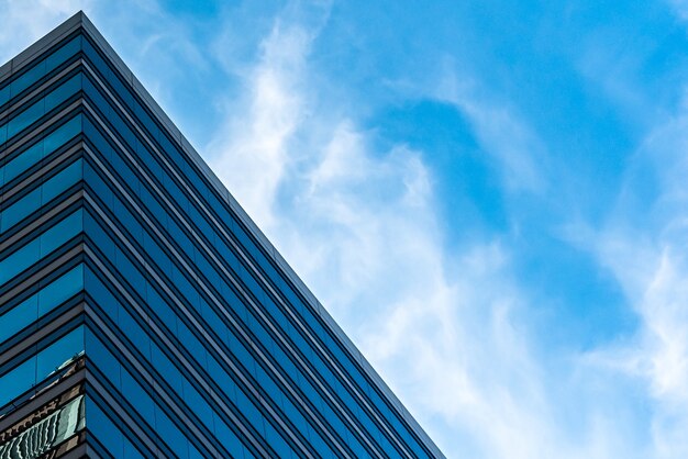 Lage hoek shot van hoge glazen gebouwen onder een bewolkte blauwe hemel