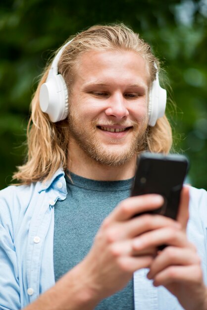 Lage hoek van smiley man met smartphone en hoofdtelefoon