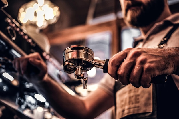 Lage hoekfoto van een barista reinigt de portafilter voordat hij de cappuccino in een coffeeshop of restaurant bereidt. detailopname