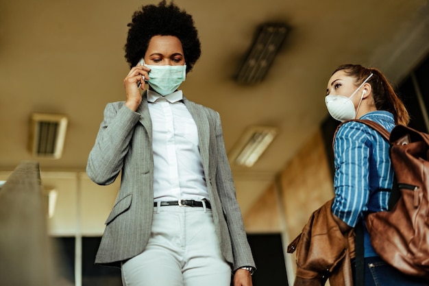 Lage hoekmening van vrouwen met beschermende maskers die elkaar passeren tijdens het wandelen op de luchthaventerminal tijdens een virusepidemie