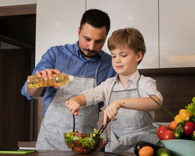 Lage hoekvader en zoon die salade maken