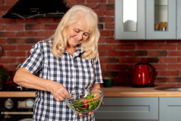 Lage hoekvrouw die salade mengt