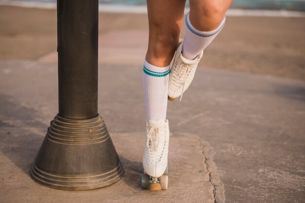 Lage sectie van een vrouwelijke schaatser die zich op één been dichtbij de pijler bevindt