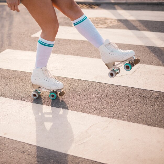 Lage sectie van vrouwelijke skater die op zebrapad schaatst