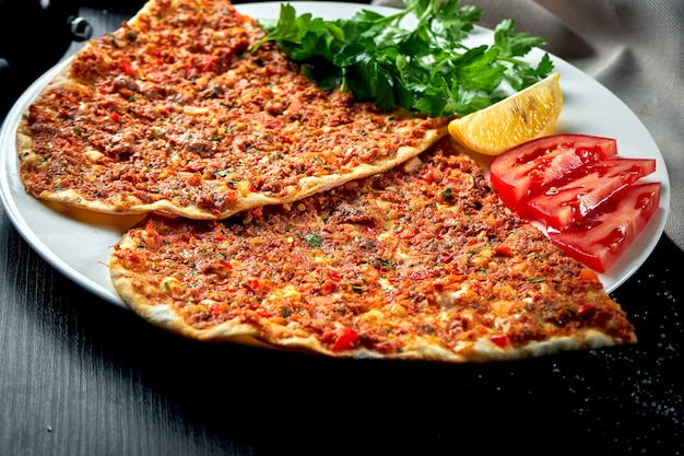 Lahmacun is een populair turks gerecht. dunne knapperige tortilla met lamsgehakt, tomaten en paprika op zwarte tafel
