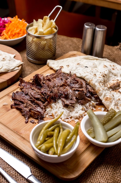 Gratis foto lamsdöner kebab geserveerd bovenop rijst met flatbread en augurken