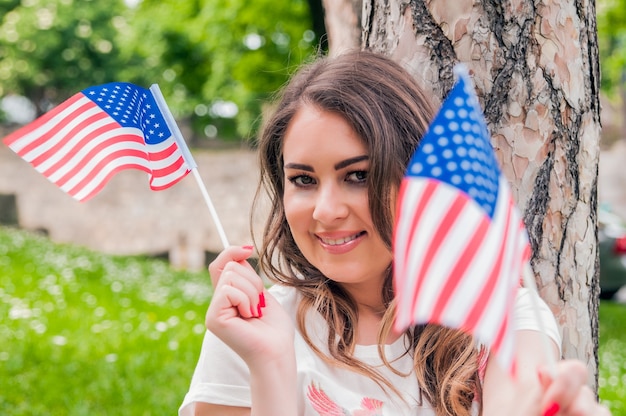 Land, patriottisme, onafhankelijkheidsdag en mensenconcept - gelukkige lachende jonge vrouw in witte jurk met nationale Amerikaanse vlag