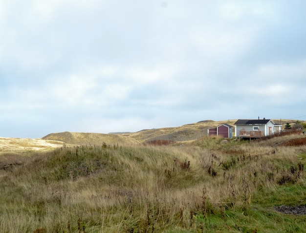 Landschap dat van een droog grasgebied is ontsproten met een huis zichtbaar in de afstand