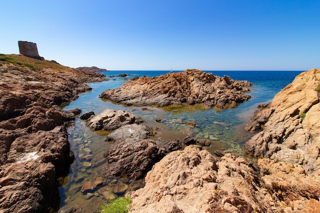 Landschap dat van grote rotsen in een blauwe oceaan met een duidelijke blauwe hemel is ontsproten