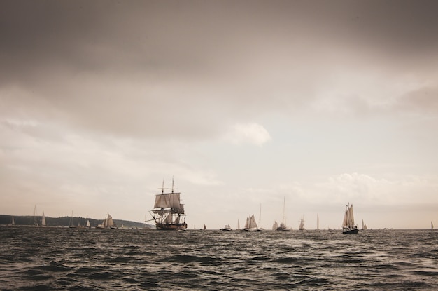 Landschap van de zee met zeilschepen erop onder een bewolkte hemel in de avond