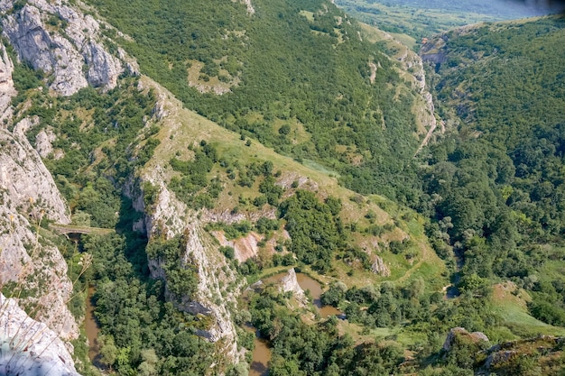 Landschap van rotsen bedekt met groen onder een blauwe lucht en zonlicht