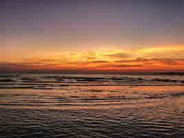 Gratis foto landschap van zonsondergang op het strand met kalmerende golven van de oceaan