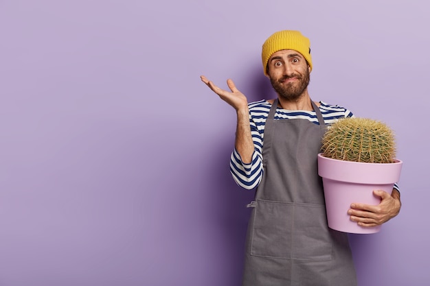 Landschapstuinieren en landbouw concept. Onzekere mannelijke bloemist gebaren met twijfel