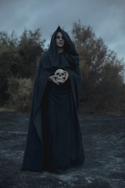 Lang portret van een man gekleed als donkere magiër met schedel